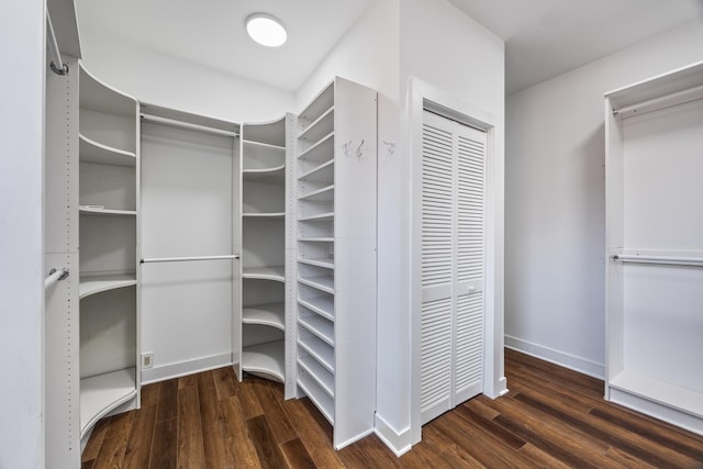 walk in closet with dark hardwood / wood-style flooring