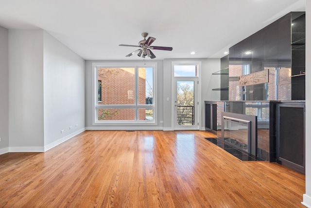 unfurnished living room featuring ceiling fan, light wood-type flooring, and a fireplace