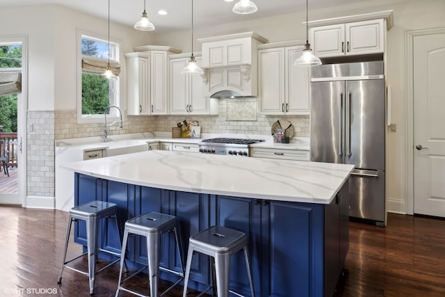 kitchen featuring light stone countertops, appliances with stainless steel finishes, a center island, and dark hardwood / wood-style flooring