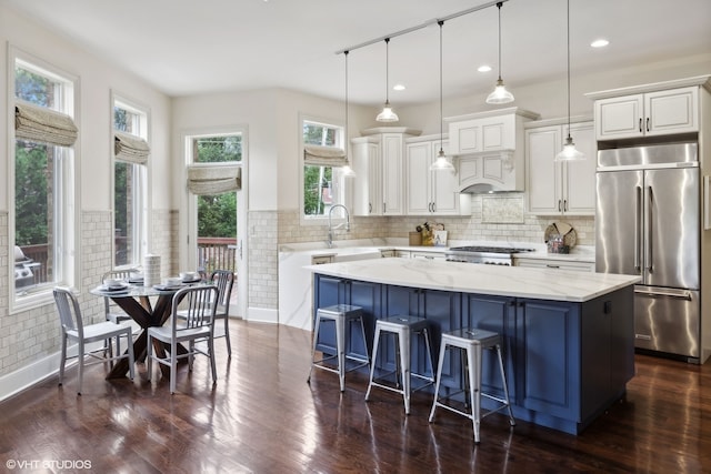 kitchen featuring a center island, stainless steel appliances, light stone counters, dark hardwood / wood-style floors, and pendant lighting