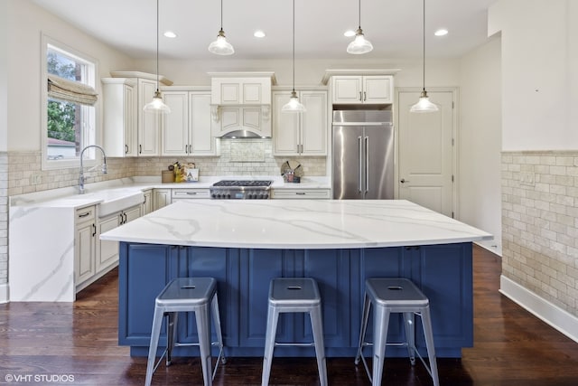 kitchen featuring sink, a kitchen island, stainless steel appliances, and decorative light fixtures