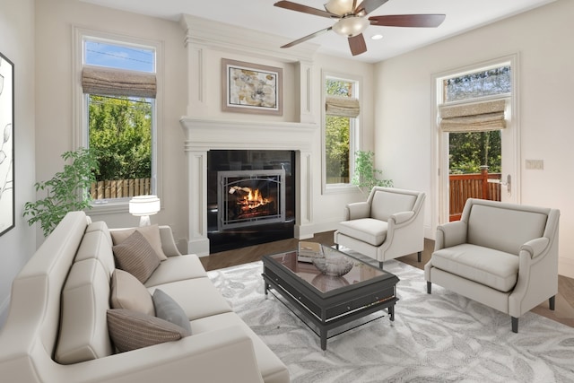 sitting room with a large fireplace, ceiling fan, plenty of natural light, and hardwood / wood-style floors