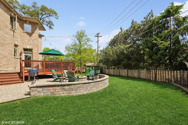 view of yard with a patio area, a storage unit, a deck, and an outdoor fire pit