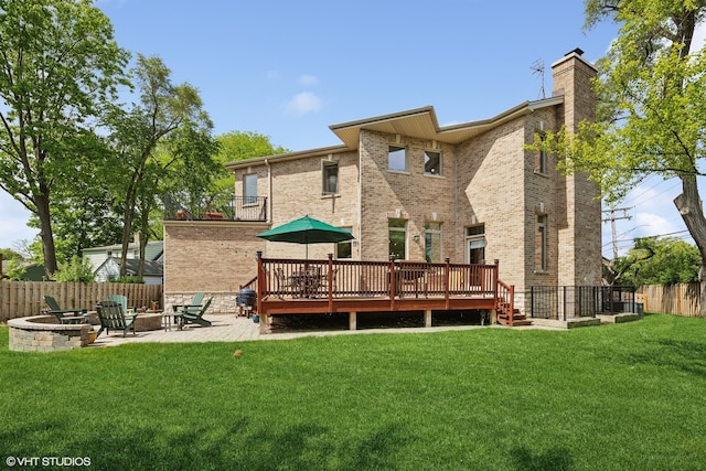 back of house with a fire pit, a patio area, a yard, and a wooden deck