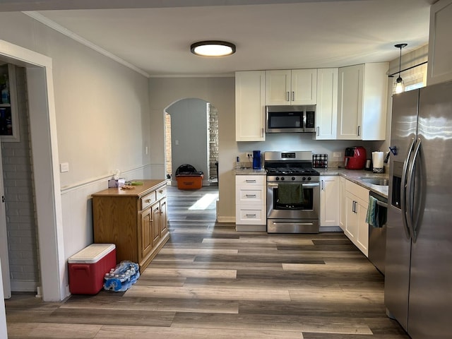 kitchen featuring hanging light fixtures, dark hardwood / wood-style floors, ornamental molding, white cabinetry, and stainless steel appliances