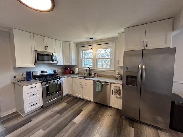 kitchen featuring pendant lighting, white cabinets, stainless steel appliances, and sink