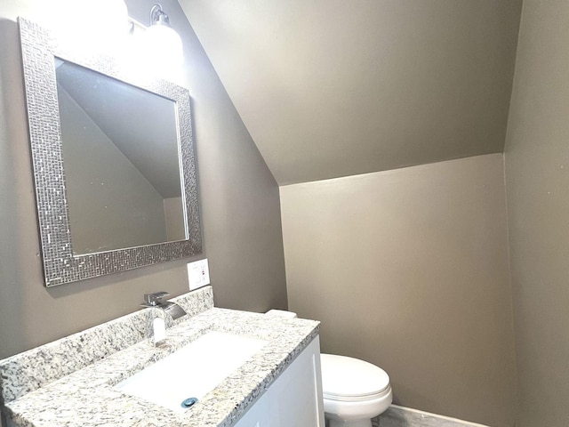 bathroom with vanity, vaulted ceiling, and toilet