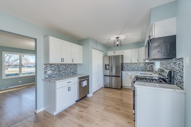 kitchen with light hardwood / wood-style floors, white cabinetry, appliances with stainless steel finishes, and tasteful backsplash