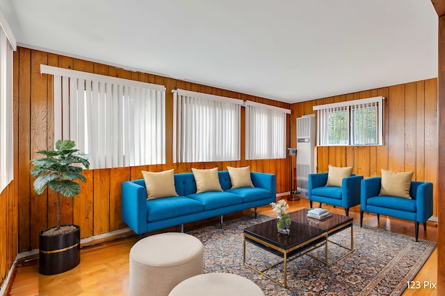 living room with light hardwood / wood-style floors and wood walls