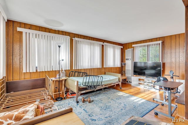 workout area featuring wooden walls, ceiling fan, baseboards, and light wood finished floors