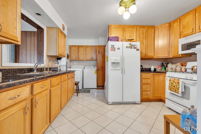 kitchen with sink, washing machine and dryer, white appliances, and dark stone countertops