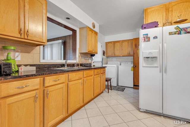 kitchen with decorative backsplash, washer and clothes dryer, a sink, dark stone countertops, and white fridge with ice dispenser