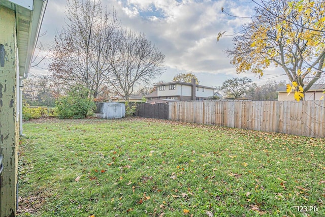 rear view of property featuring fence, a storage shed, a chimney, an outdoor structure, and a yard