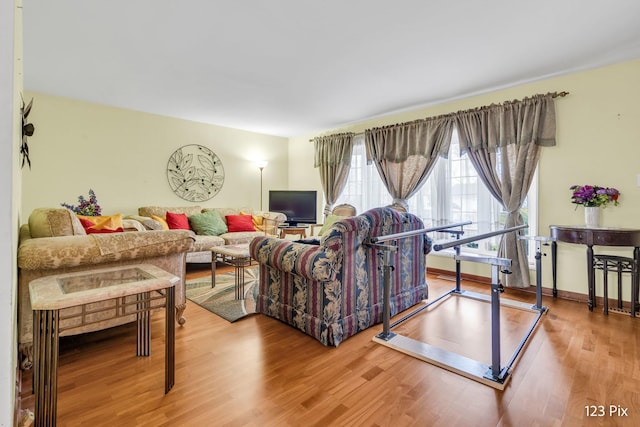 living room with a healthy amount of sunlight, baseboards, and wood finished floors