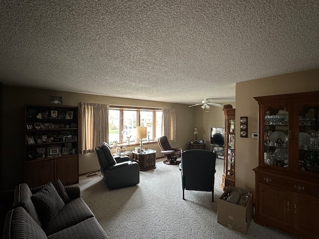 living room featuring carpet flooring, ceiling fan, and a textured ceiling