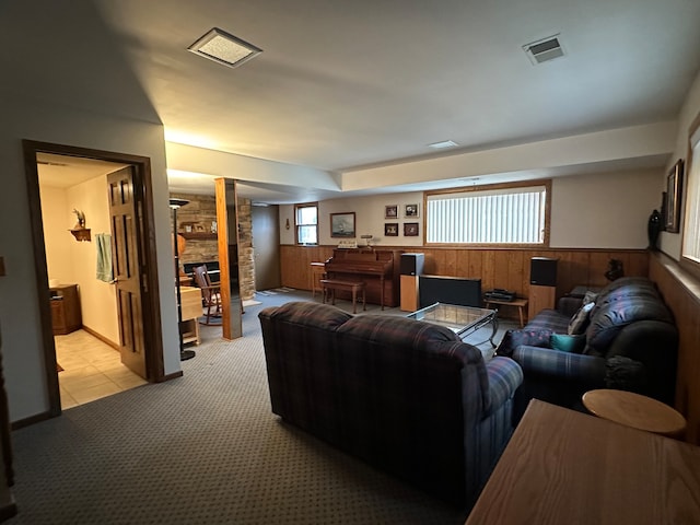 living room featuring a fireplace, light colored carpet, and wooden walls