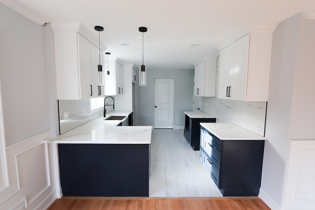 kitchen with decorative backsplash, sink, white cabinets, and pendant lighting