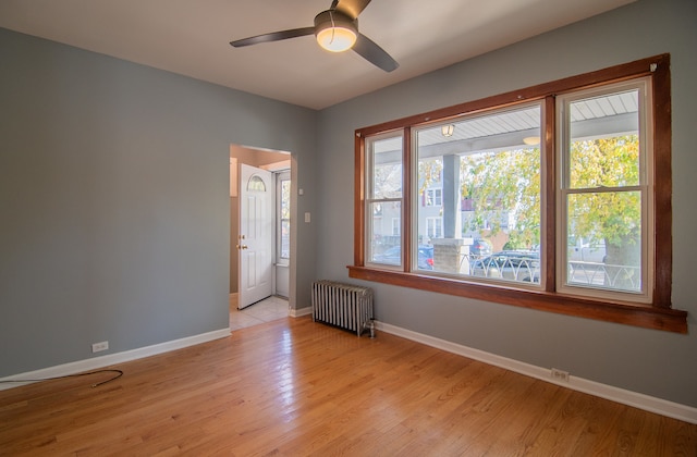 spare room with ceiling fan, light hardwood / wood-style floors, and radiator heating unit