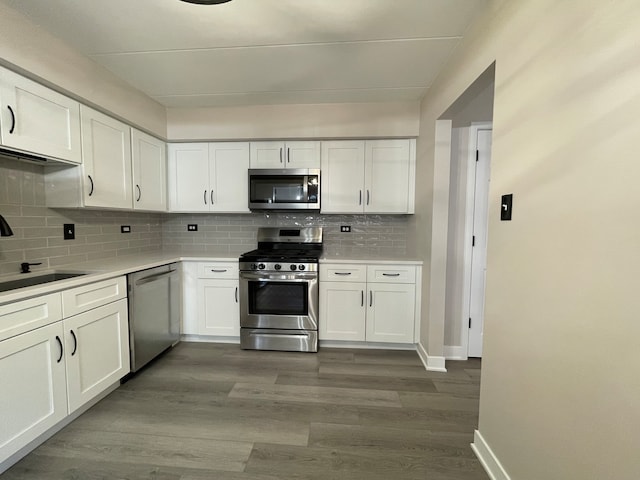 kitchen with backsplash, white cabinetry, hardwood / wood-style floors, and stainless steel appliances