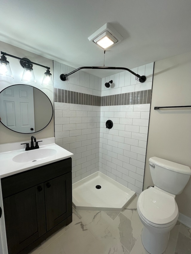 bathroom featuring vanity, toilet, and a tile shower