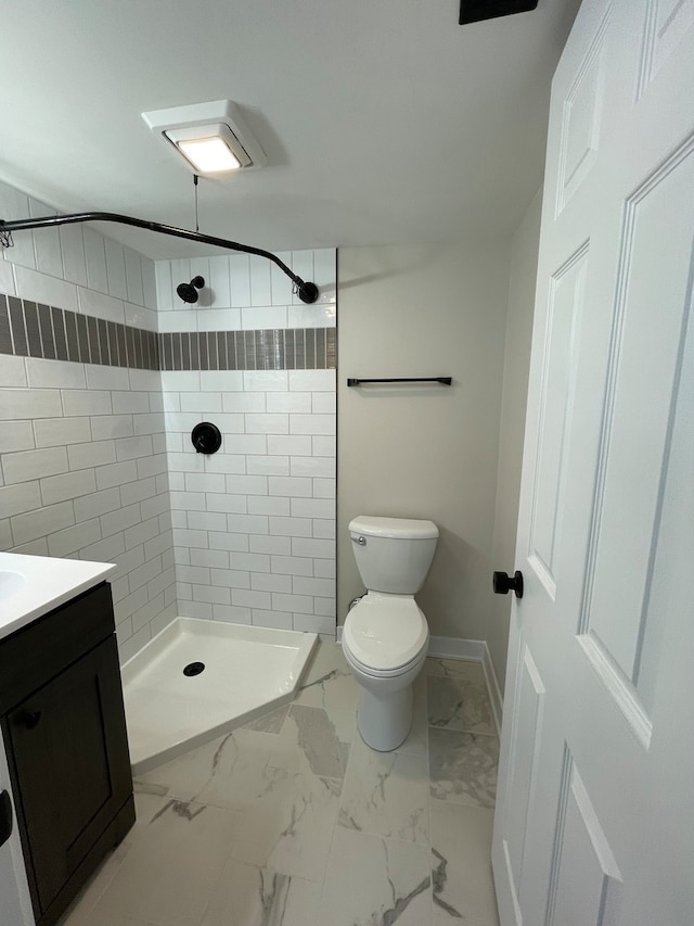 bathroom with tiled shower, vanity, and toilet