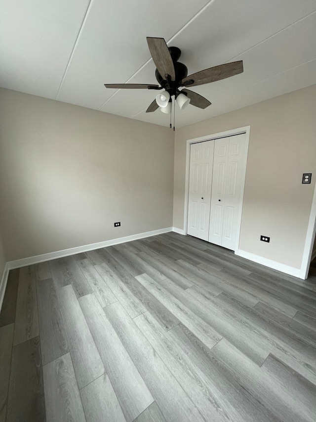 unfurnished bedroom featuring wood-type flooring, a closet, and ceiling fan