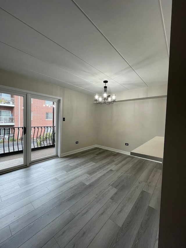 empty room with hardwood / wood-style floors and a notable chandelier