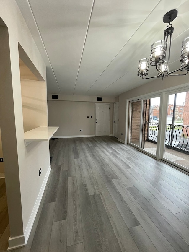 unfurnished living room featuring wood-type flooring and an inviting chandelier