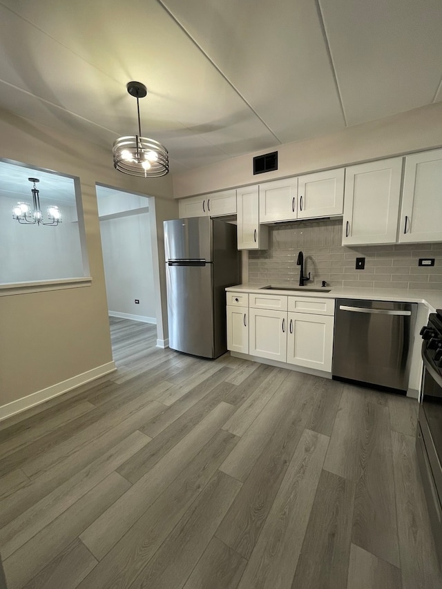 kitchen featuring pendant lighting, white cabinets, sink, and appliances with stainless steel finishes