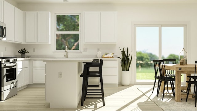 kitchen featuring sink, stainless steel appliances, light hardwood / wood-style floors, a kitchen bar, and white cabinets