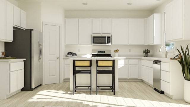 kitchen with white cabinets, a center island, light wood-type flooring, and stainless steel appliances