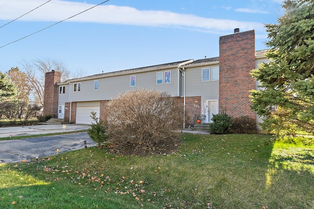 rear view of property featuring a garage and a lawn