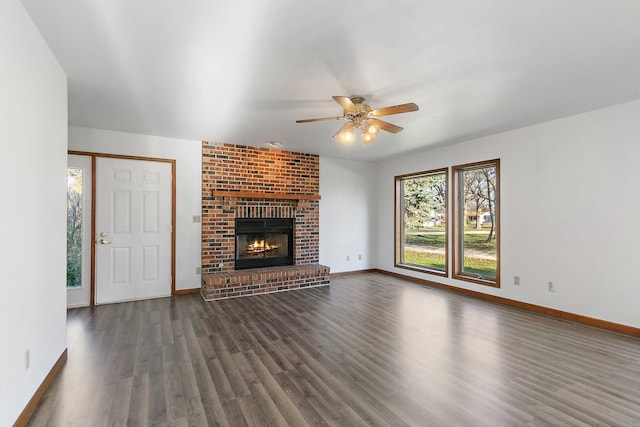 unfurnished living room featuring ceiling fan, dark hardwood / wood-style flooring, and a brick fireplace