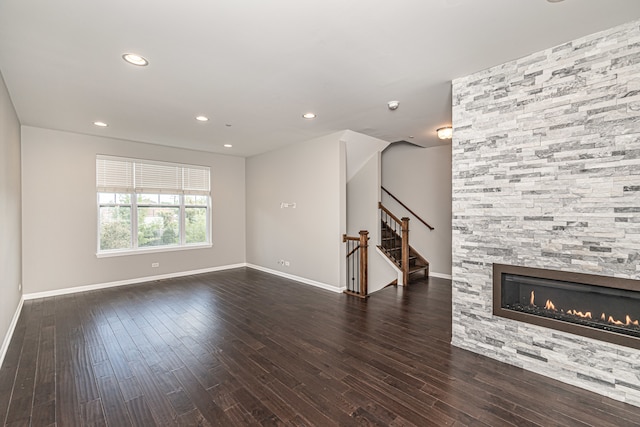 unfurnished living room with dark hardwood / wood-style flooring and a stone fireplace