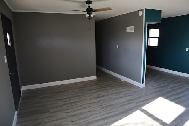 empty room featuring ceiling fan, crown molding, and dark wood-type flooring