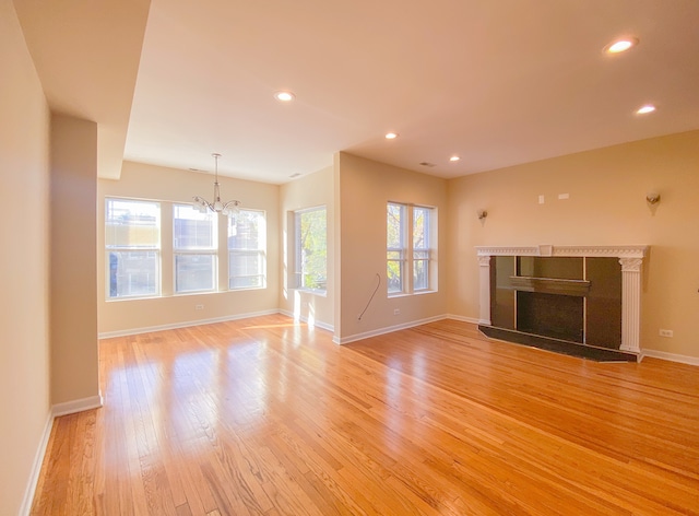 unfurnished living room with a notable chandelier and light hardwood / wood-style flooring