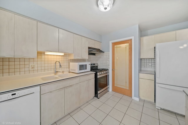 kitchen featuring light tile patterned floors, under cabinet range hood, white appliances, a sink, and light countertops