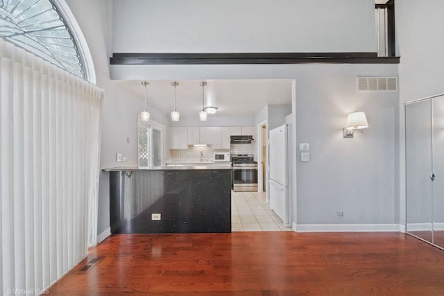 kitchen featuring white appliances, visible vents, under cabinet range hood, and white cabinets