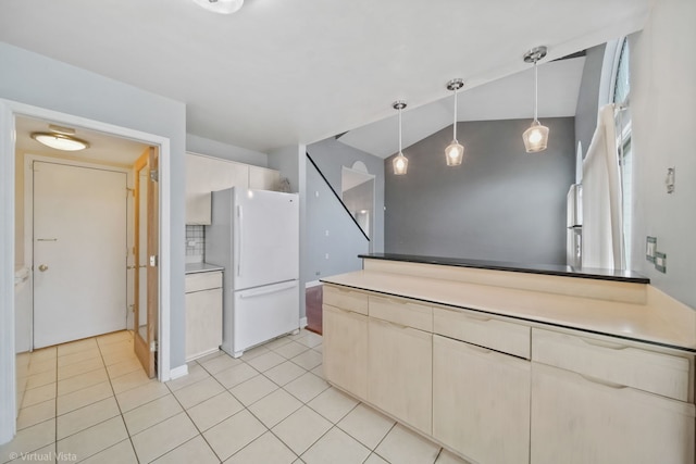 kitchen with light tile patterned floors, hanging light fixtures, freestanding refrigerator, and decorative backsplash