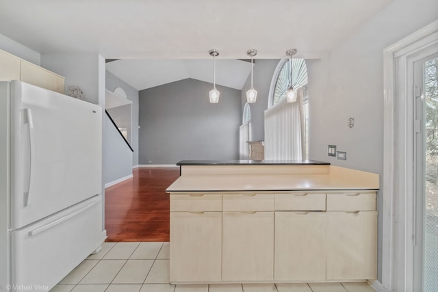 kitchen featuring light tile patterned floors, baseboards, vaulted ceiling, freestanding refrigerator, and decorative light fixtures