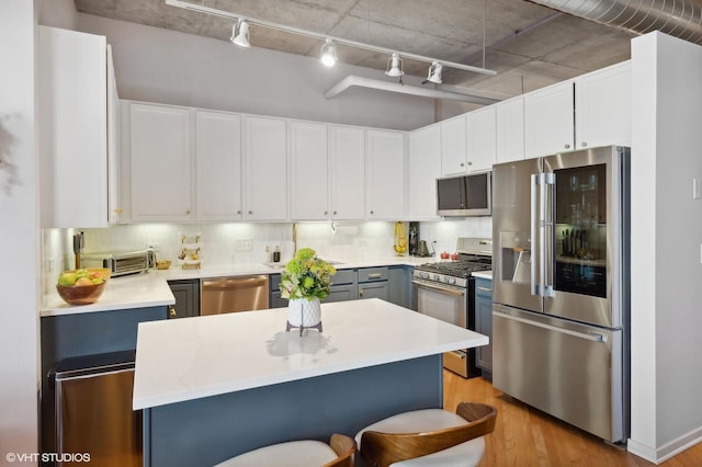 kitchen featuring light wood-style floors, tasteful backsplash, appliances with stainless steel finishes, and light countertops