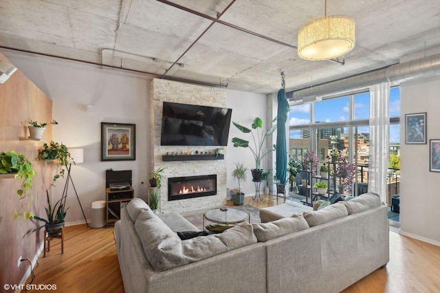 living area featuring a stone fireplace, wood finished floors, and baseboards