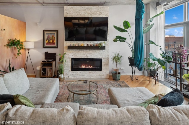 living area with a stone fireplace, wood finished floors, and baseboards