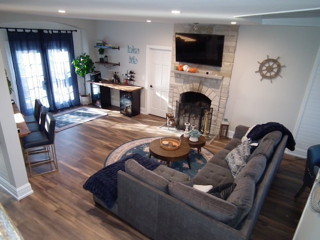 living room featuring hardwood / wood-style floors, a stone fireplace, and vaulted ceiling