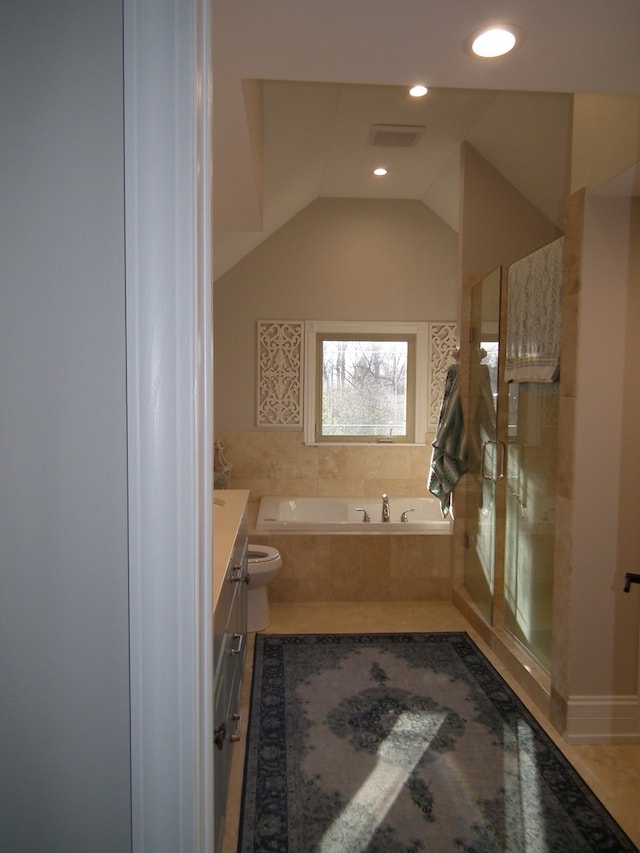 bathroom with tile patterned floors, vanity, lofted ceiling, and tiled bath