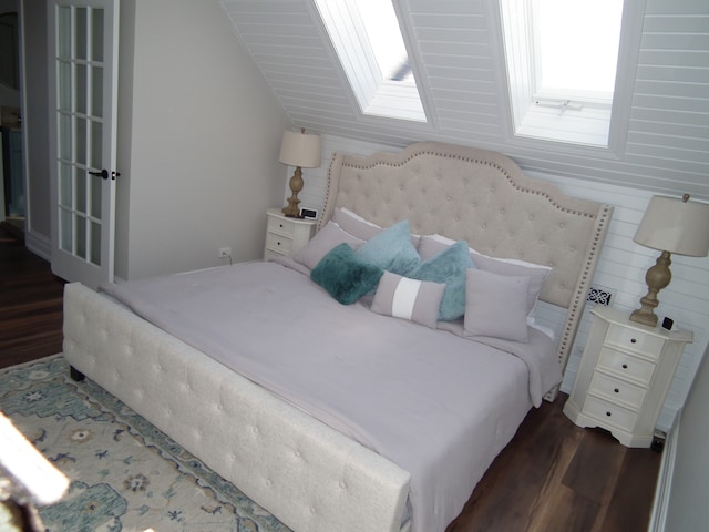 bedroom with a skylight, wooden walls, and dark hardwood / wood-style floors