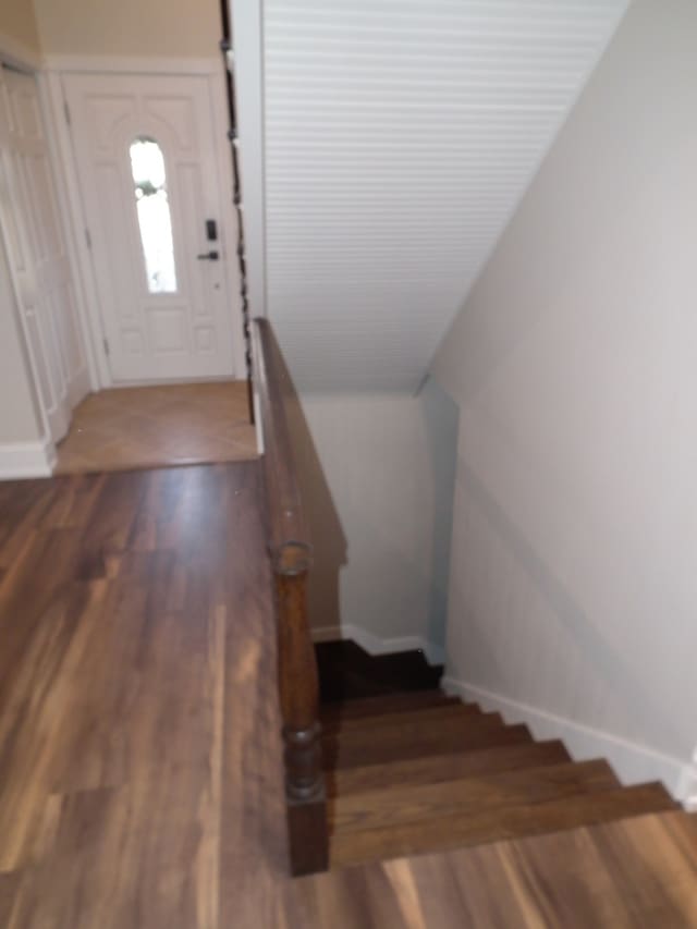 stairs with wood-type flooring and vaulted ceiling