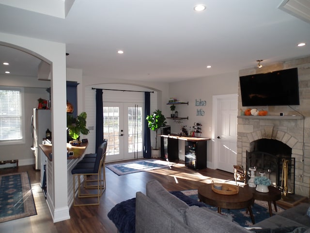 living room with a stone fireplace, wood-type flooring, and french doors