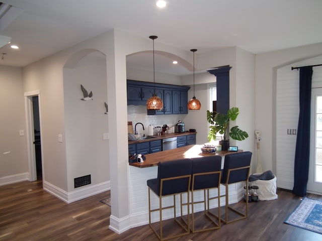 kitchen featuring wood counters, dark hardwood / wood-style flooring, blue cabinets, and a wealth of natural light