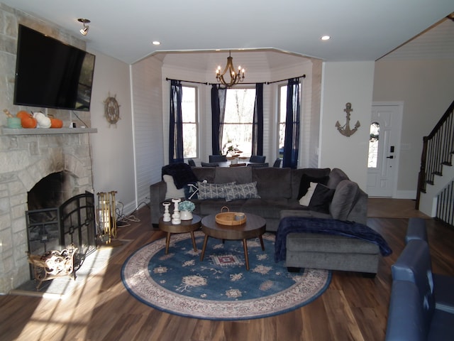 living room featuring a notable chandelier, wood-type flooring, a fireplace, and ornamental molding